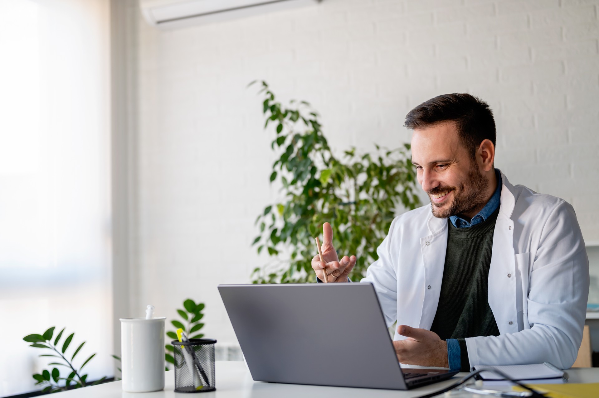 The doctor working in his office giving consultations online over the internet using his laptop computer